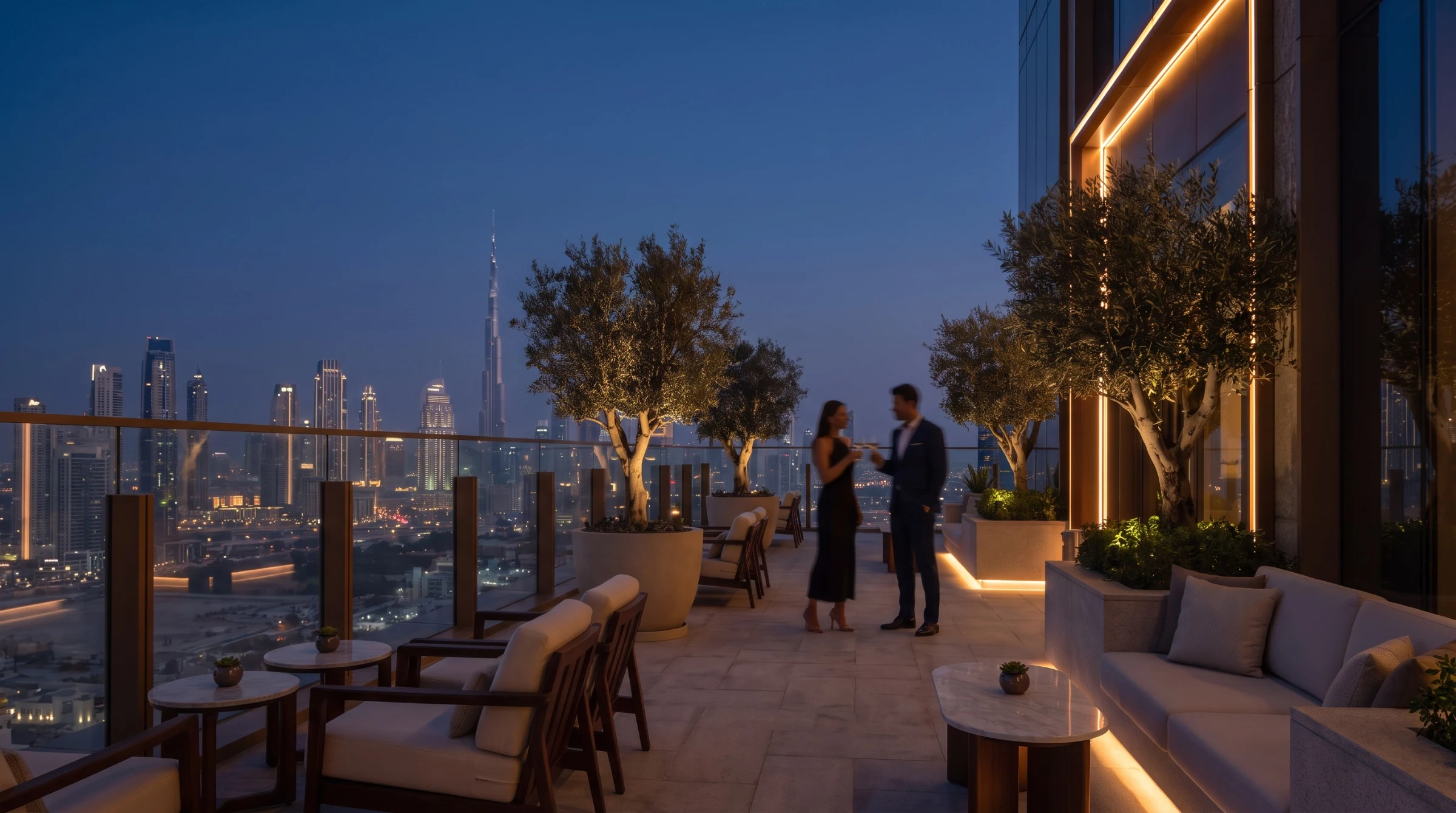 Guests talking on a rooftop restaurant terrace overlooking the Dubai skyline at dusk.